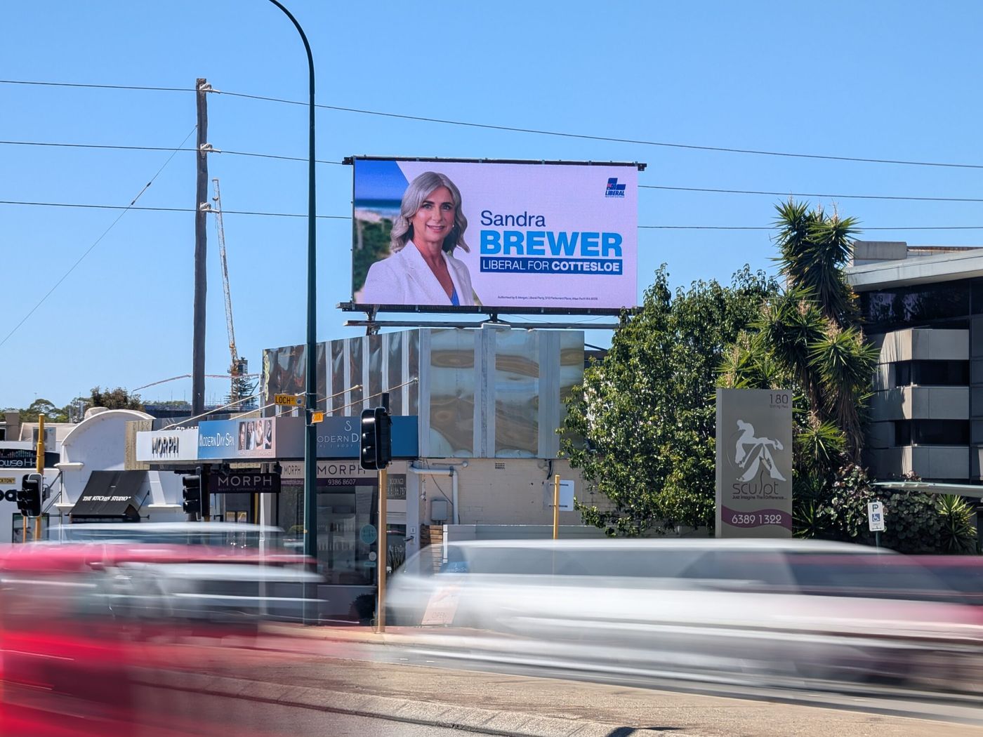 Pole-mounted digital screen on Stirling Highway with traffic passing.